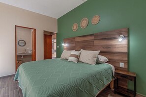Ein Schlafzimmer mit grüner Wand, einem hölzernen Kopfteil und einem Bett mit grüner Steude.