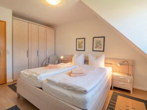 Ein Schlafzimmer mit einem Bett, zwei Nachttischen, einem Sessel und einem Kleiderschrank.