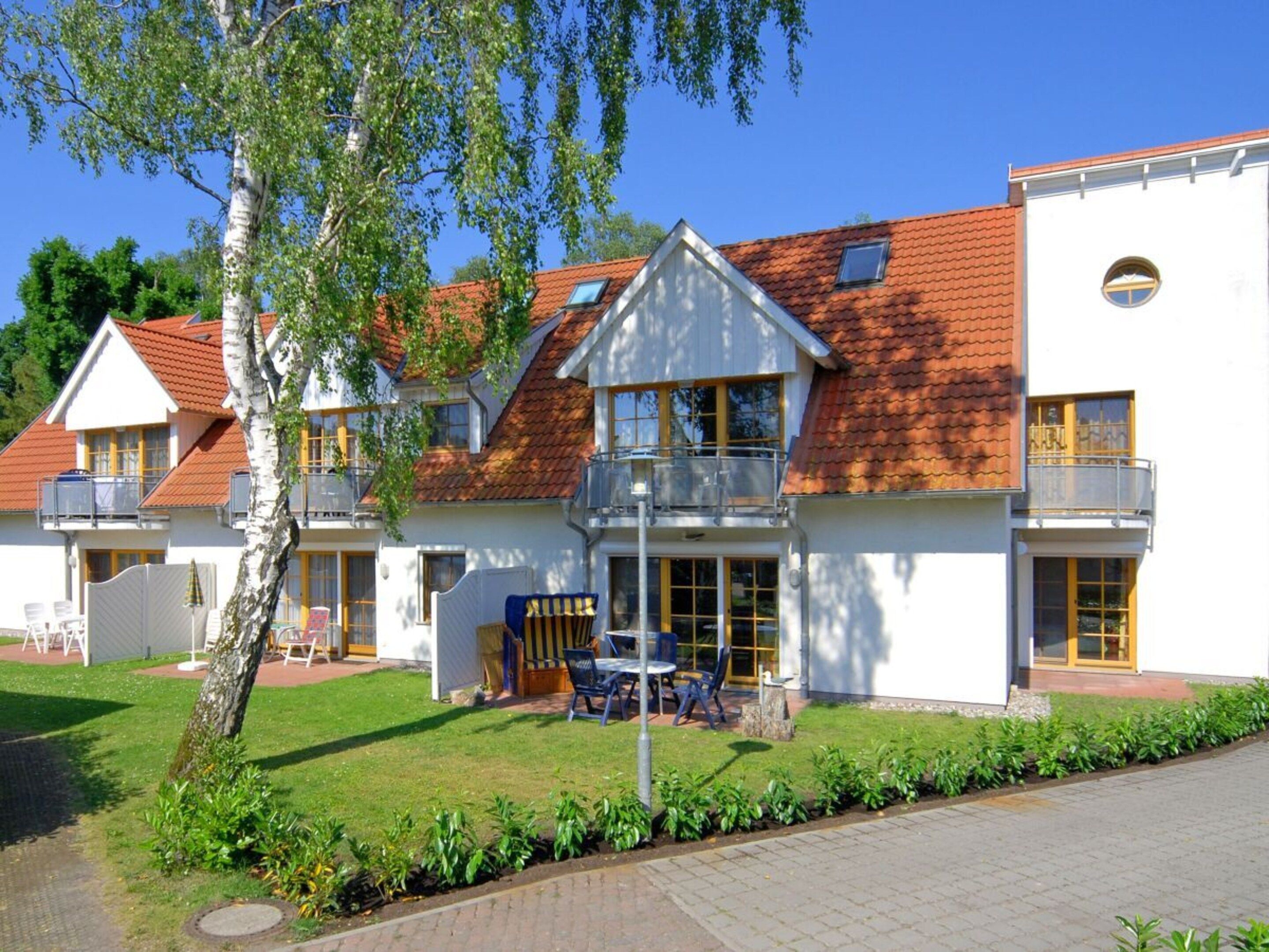 Un bâtiment à deux étages, doté d’un toit recouvert de tuiles rouges, de balcons et d’une pelouse bien entretenue.