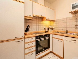 Eine kleine Küche mit Einbauofen, Mikrowelle und Spüle.