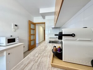 Eine moderne Küche mit integriertem Mikrowellenherd, einer Kaffeemaschine und einer Holzausziehtheke.
