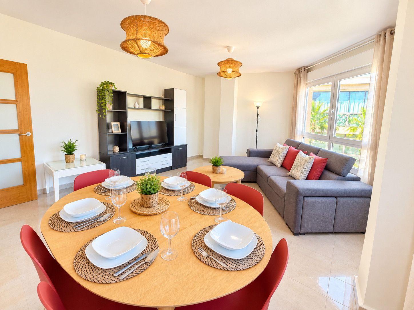 A modern living room with a dining area, a grey sofa, and a television.
