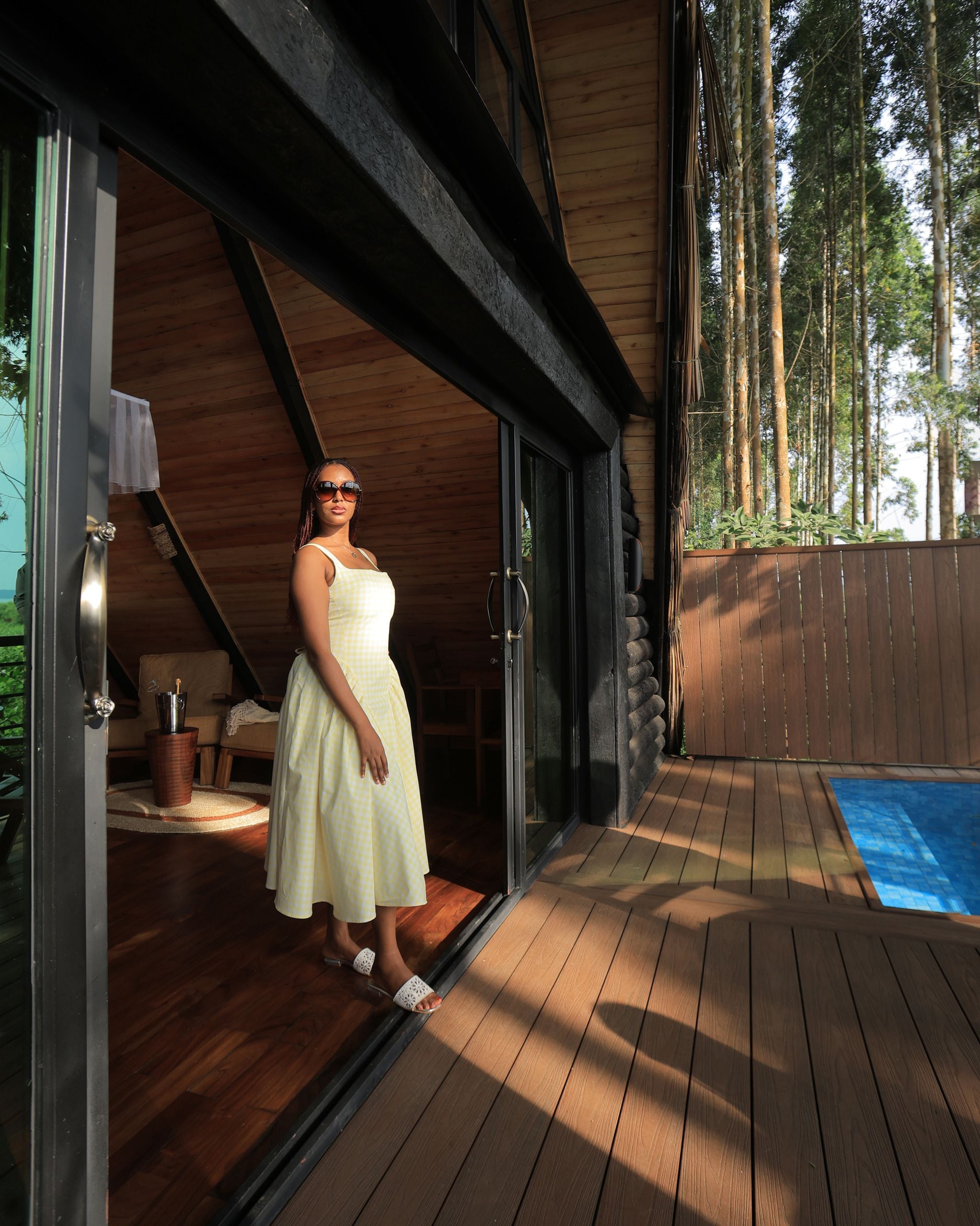 A person standing on a wooden deck with a glass door leading to a room.