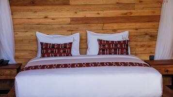 A bed with a white bedspread and two patterned pillows, set against a wooden headboard.