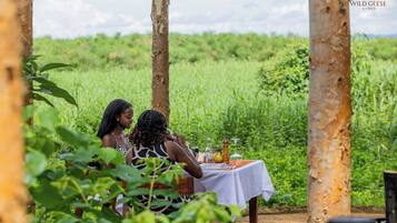 Two people dining at an outdoor table with a view of a green field.