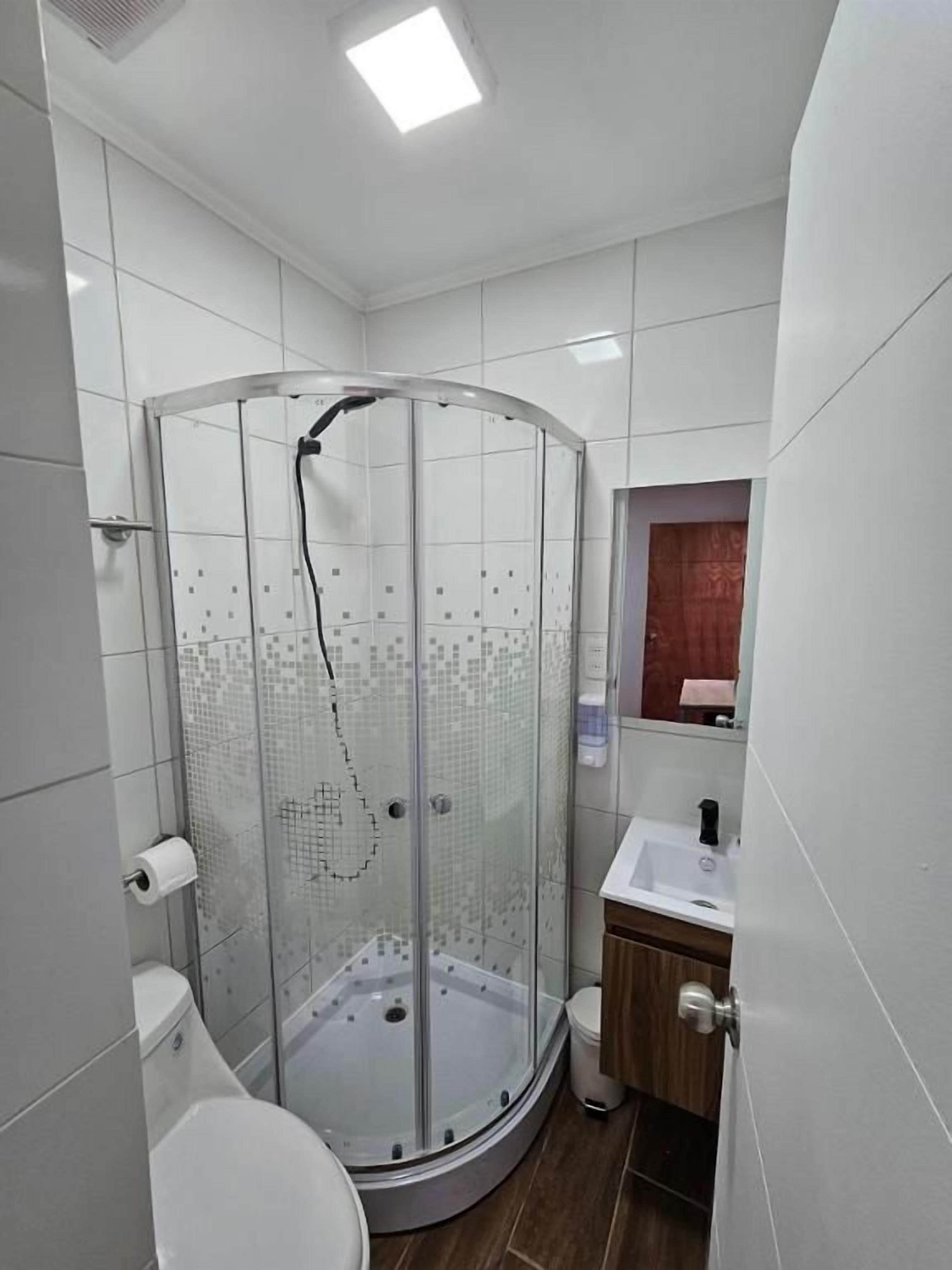 A modern bathroom with a glass-enclosed shower, a toilet, and a sink.