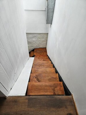 Una estrecha escalera de madera con paredes blancas.