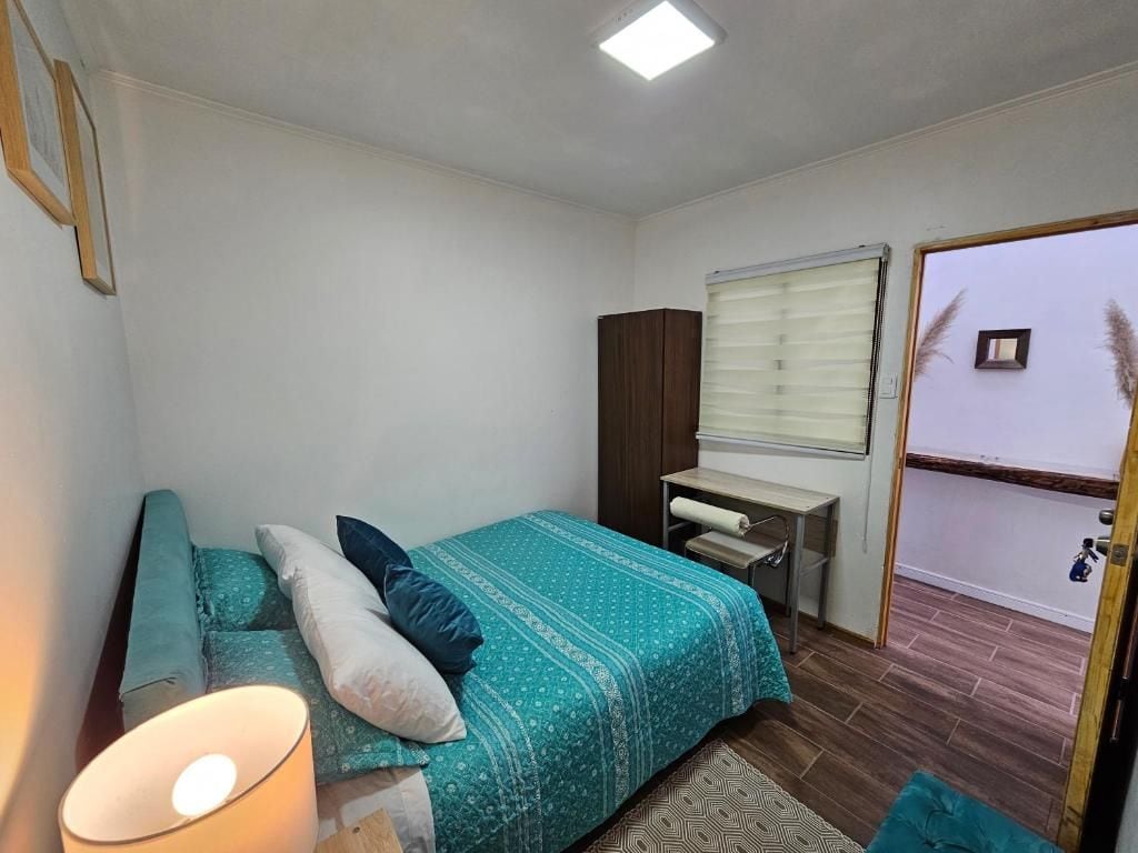 Un dormitorio con cama, escritorio, armario y ventana con persianas.