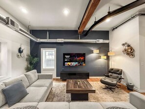 A modern living room with a sofa, a coffee table, a TV, and a fireplace. - Luxury 2BD | 4 Beds | Northern Liberties (Philadelphia)