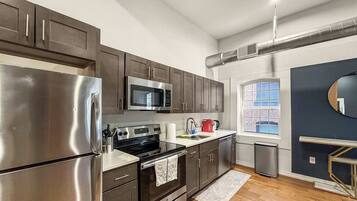 A modern kitchen with stainless steel appliances, dark cabinetry, and a window providing natural light.