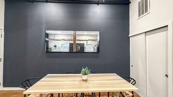 A dining area with a long wooden table, black chairs, and a small plant centerpiece.