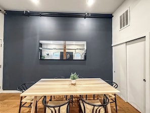 A dining area with a long wooden table, black chairs, and a small plant centerpiece. - Luxury 2BD | 4 Beds | Northern Liberties (Philadelphia)
