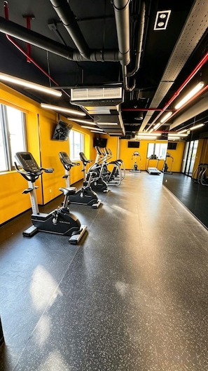 A gym with stationary bikes, treadmills, and a mirrored wall. - Luxury GTC Westlands Suite | Pool, Gym, Cinema, Sauna, Skyline Views & Mall (Nairobi)