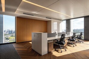 Un espacio de oficina moderno con un escritorio grande, sillas de oficina y vistas a la ciudad.