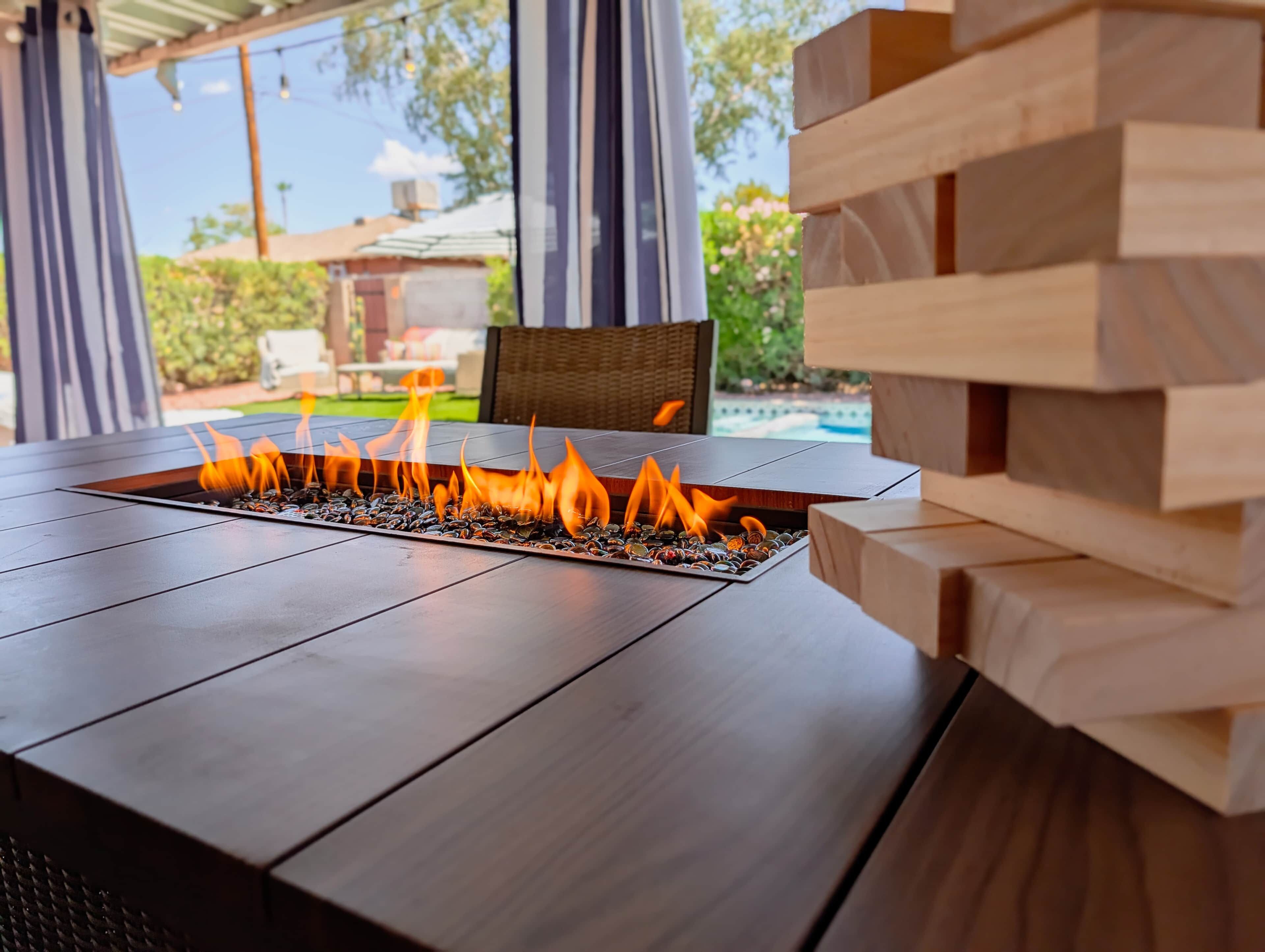 A fire feature with a clear view of a pool and greenery in the background.