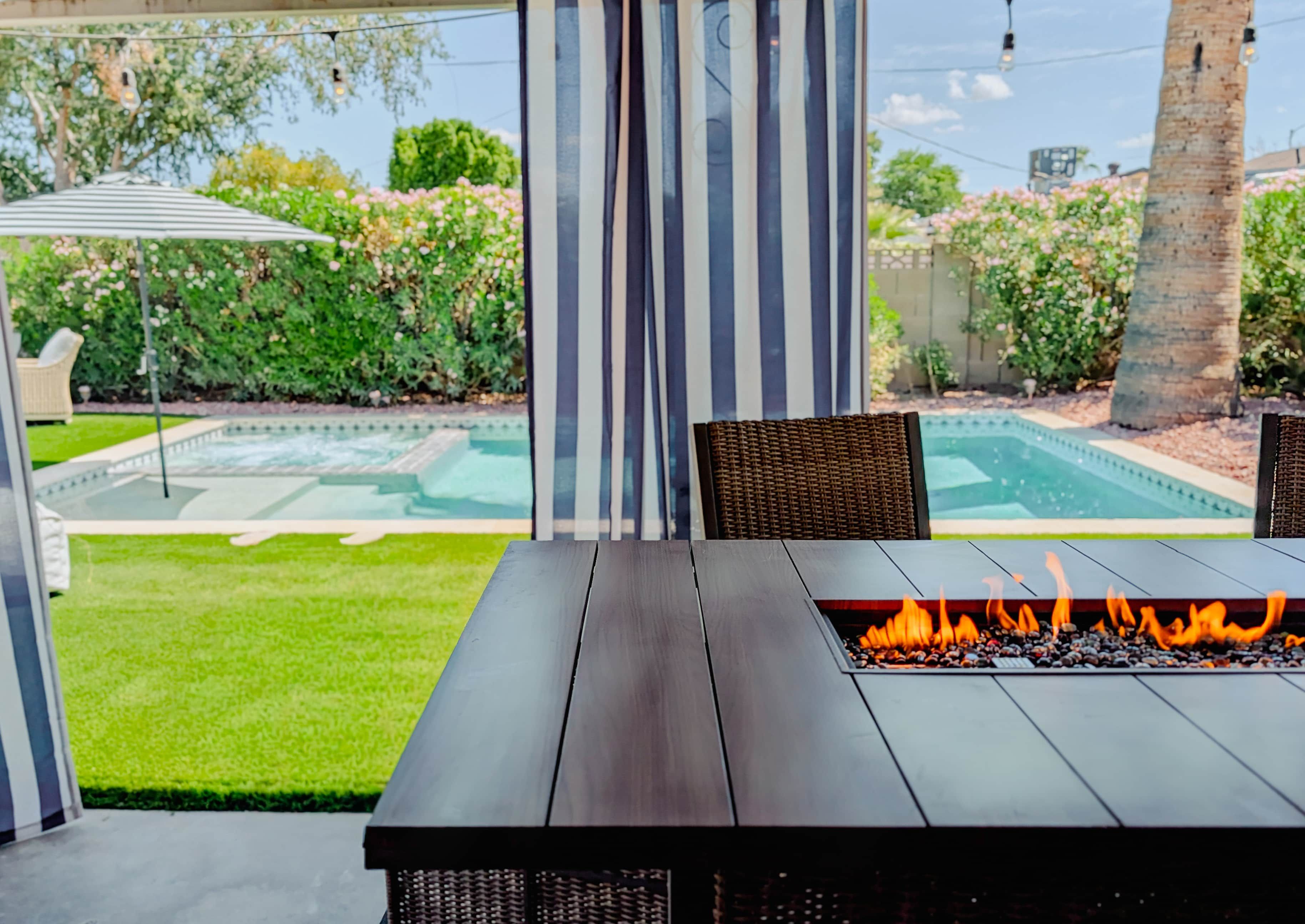 Un patio con una fogata, asientos al aire libre y vistas a una piscina.