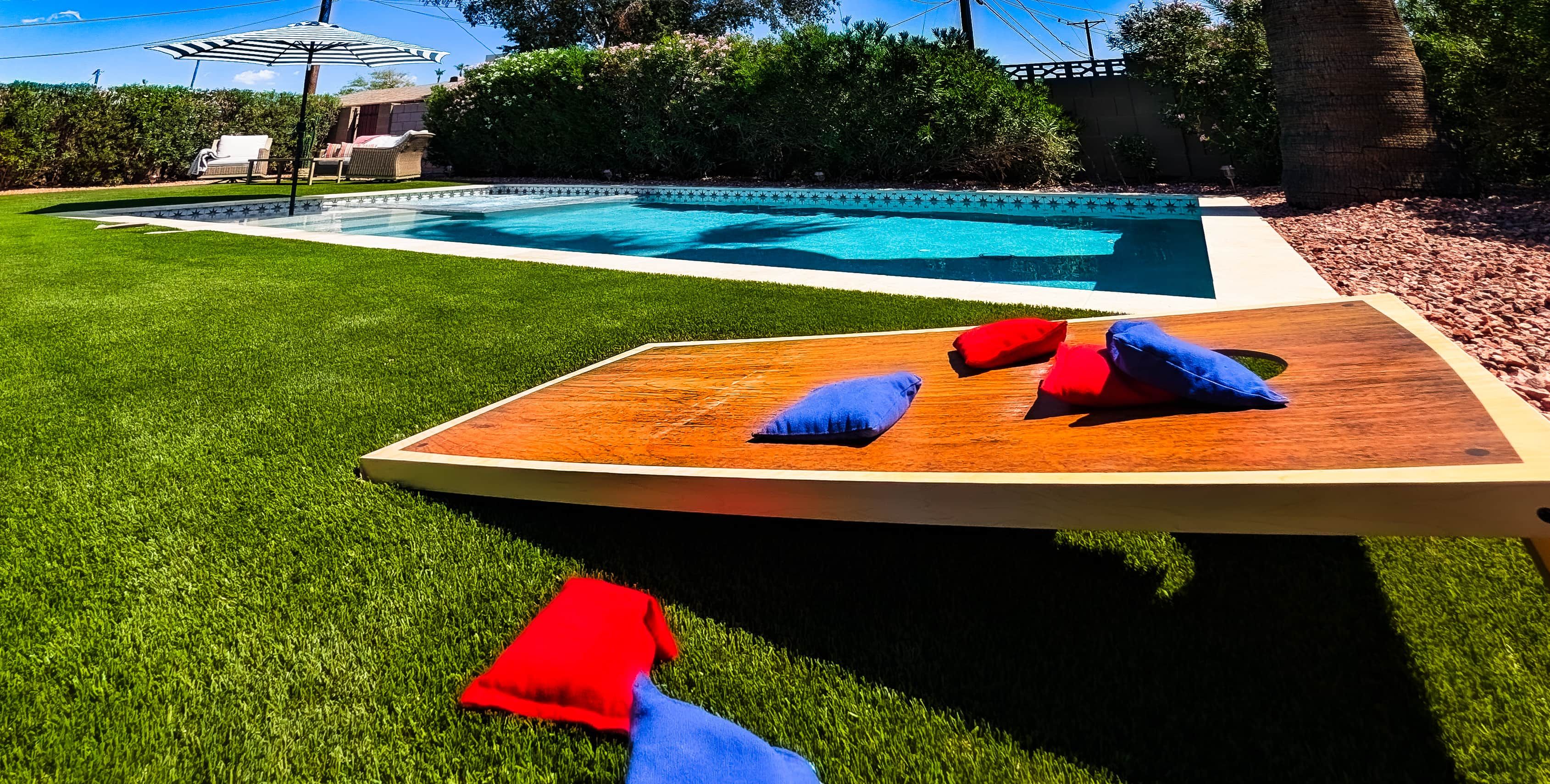 A rectangular wooden deck with a pool in the background.