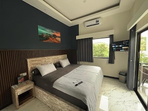 Quarto moderno com uma cama grande, mesa de cabeceira, pintura na parede, ar condicionado e televisão.