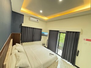 Quarto de hotel com cama, janela, porta e aparelho de ar condicionado.