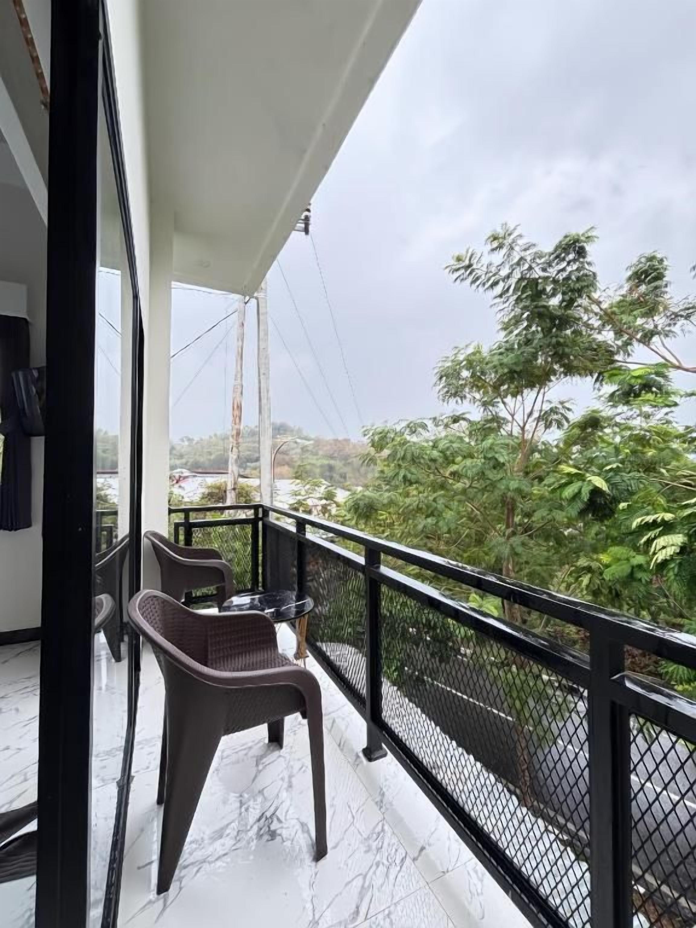 Ein Balkon mit Blick auf Grünflächen und eine ferne Landschaft.