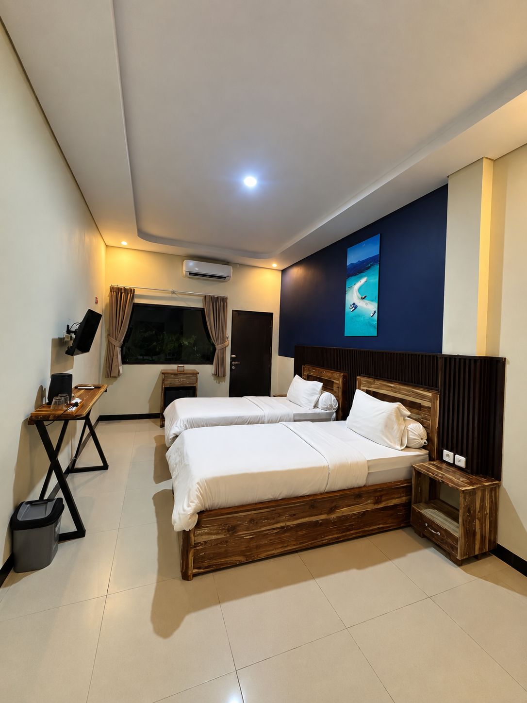 Habitación de hotel con dos camas, un escritorio, un televisor y un equipo de aire acondicionado.