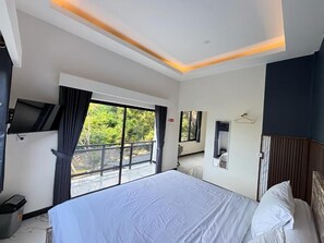 Une chambre d’hôtel avec un grand lit, une télévision, un balcon avec vue et une porte dotée d’un miroir.