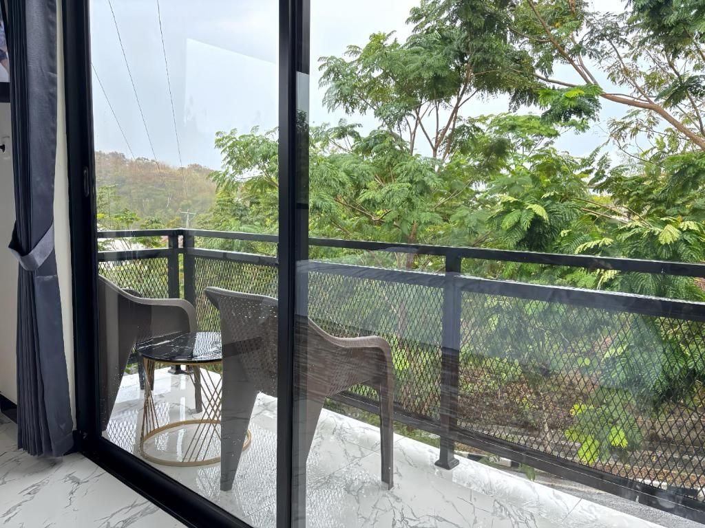 Ein Balkon mit Blick auf üppiges Grün und einem Tisch mit Stühlen.