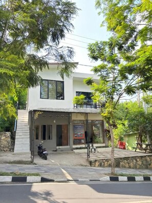 Um edifício de dois andares com entrada coberta e uma motocicleta estacionada na frente.