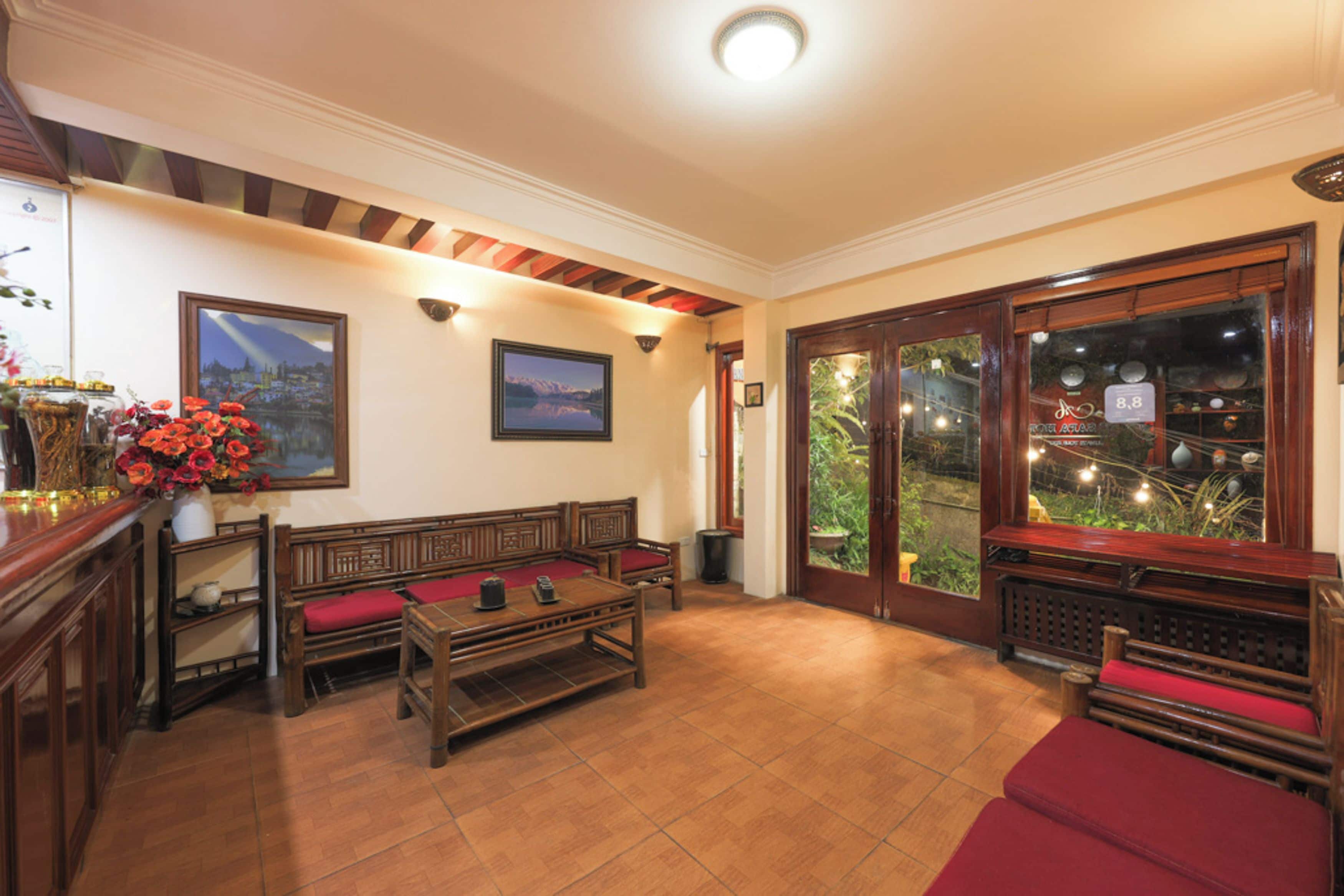 A lobby with wooden benches, a reception desk, and a large window with a view of greenery.