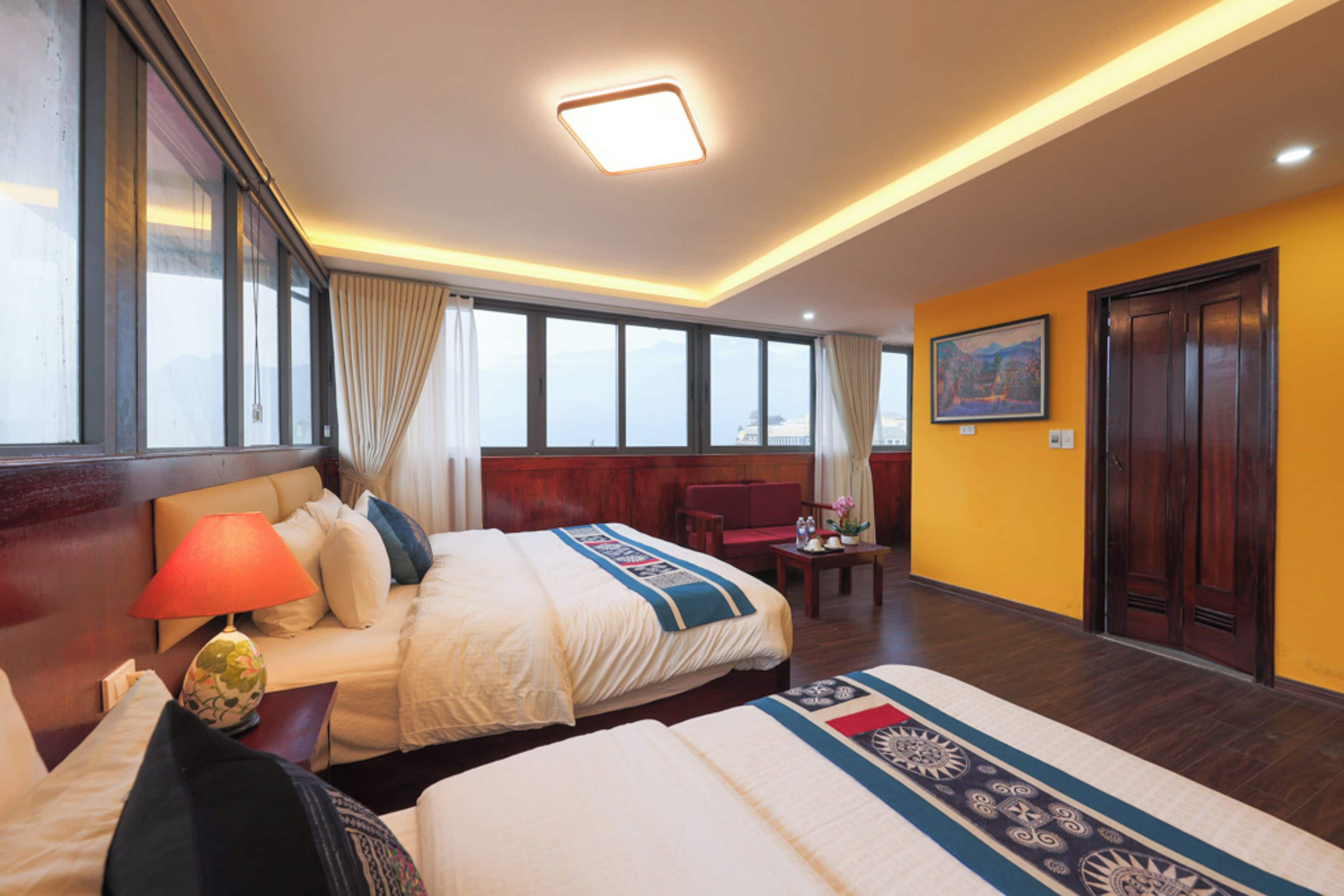 Une chambre d’hôtel avec deux lits, un bureau, une chaise, une lampe et un tableau au mur.