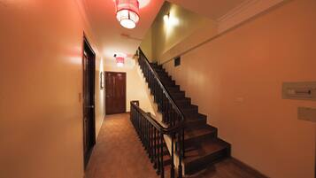 A staircase with wooden steps and a black handrail leading to an upper floor.