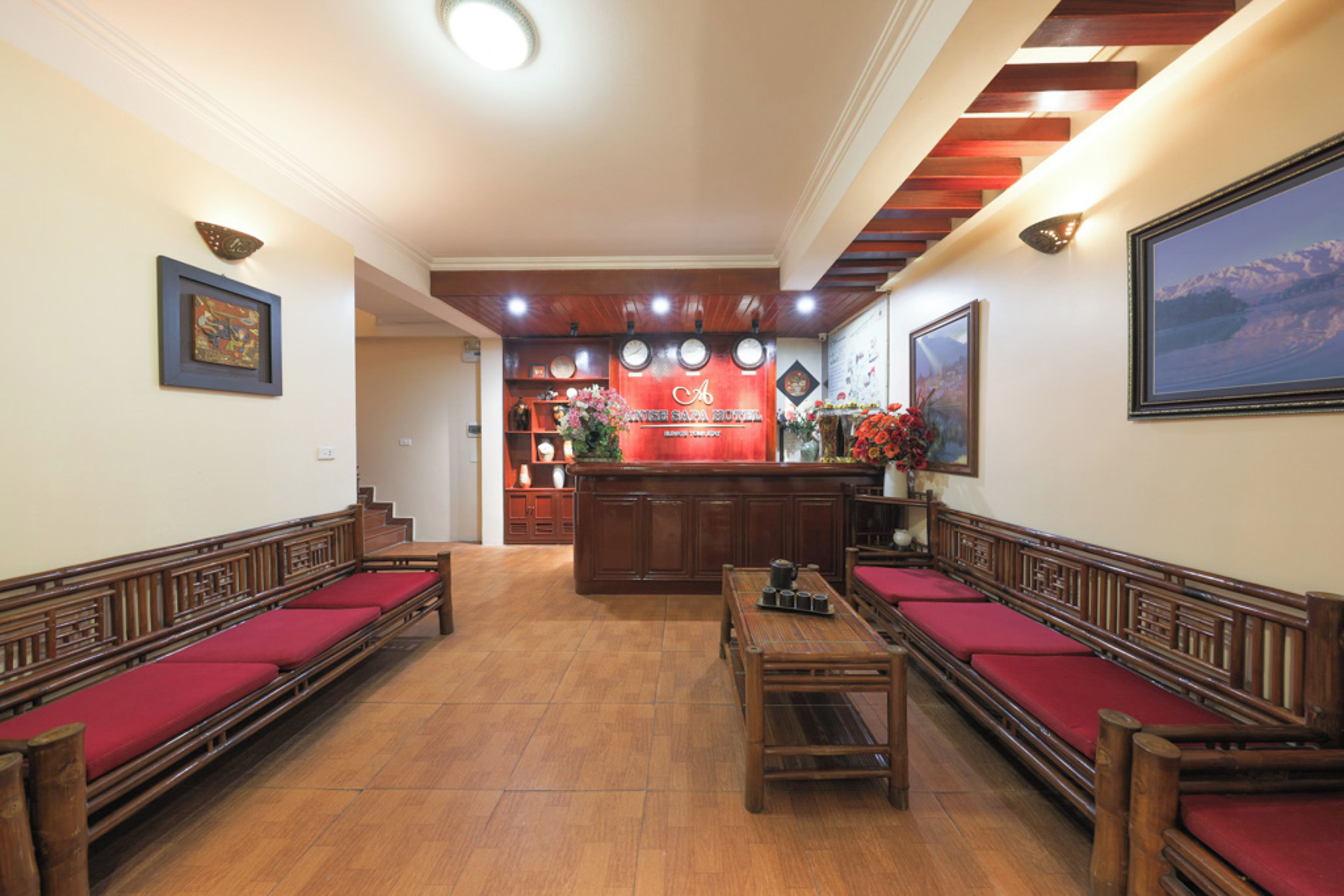 A hotel lobby with wooden benches, a reception desk, and a clock.