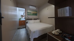 Et hotelværelse med seng, sengebord og en reol med bøger.