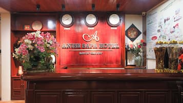 A reception desk with clocks, a floral arrangement, and a wall with a map and awards.