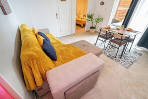Une pièce confortable avec un lit, une petite table agrémentée d’une plante et un coin repas avec des chaises.