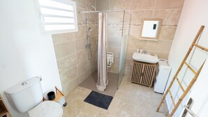 Un bagno con doccia, servizi igienici, lavandino e un piccolo armadietto in legno.