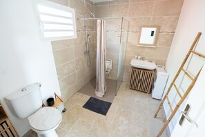 Une salle de bain équipée d’une douche, de toilettes, d’un lavabo et d’un petit meuble en bois.