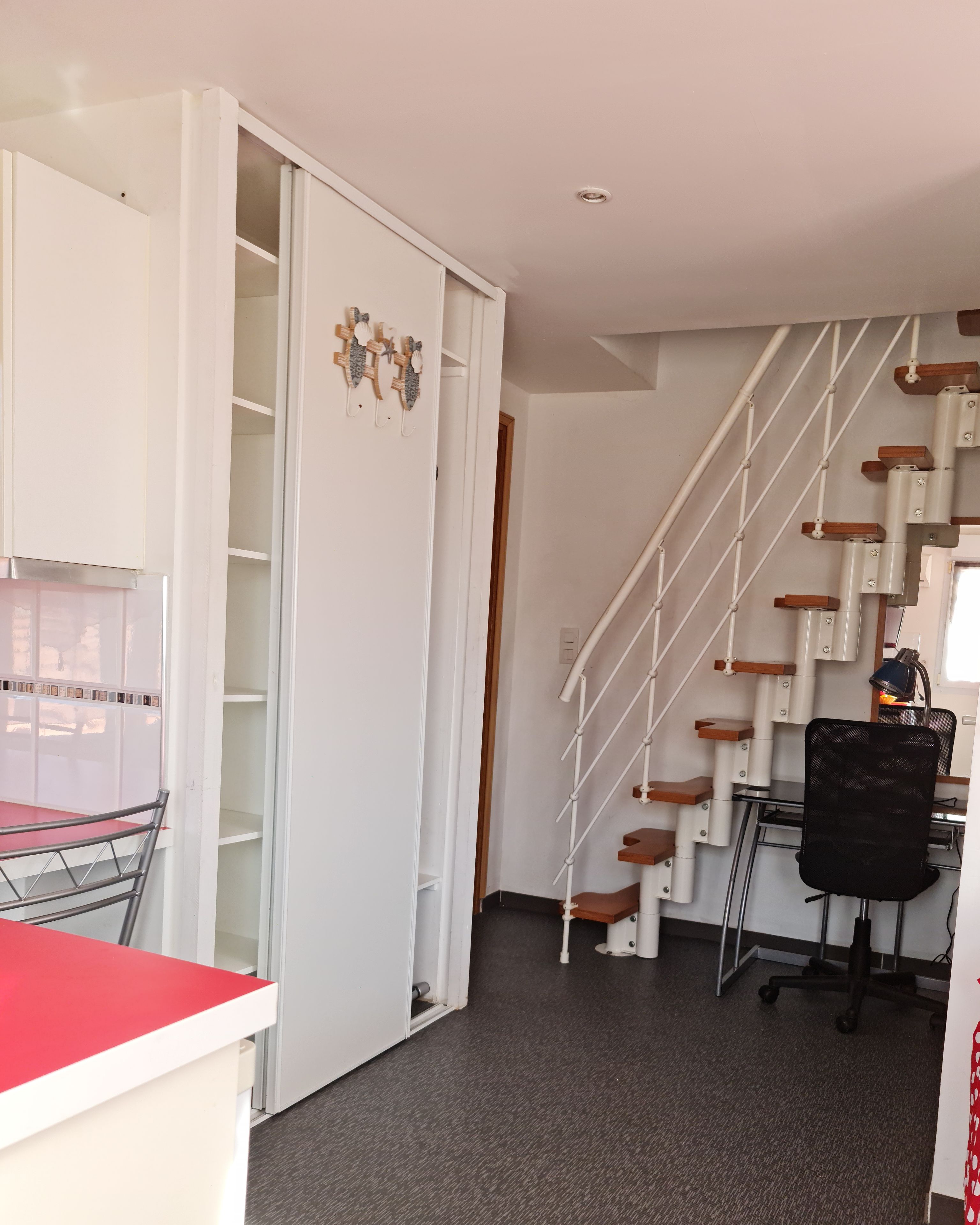 Una habitación con un escritorio, una silla y una escalera de madera.