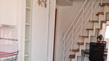 Una habitación con un escritorio, una silla y una escalera de madera.