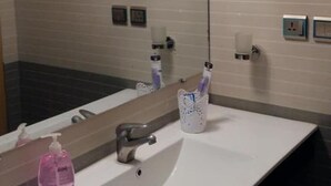 Un baño con lavamanos, espejo y perchero para toallas.