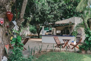 A rustic outdoor seating area with wooden furniture, a stone-paved ground, and lush greenery. - Quinta Risas del Sol (Brisas de Zicatela)