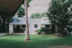 A courtyard with a building, a palm tree, and a grassy area. - Quinta Risas del Sol (Brisas de Zicatela)