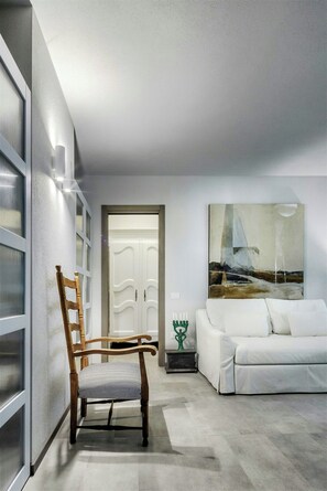 Ein modernes Wohnzimmer mit einem weißen Sofa, einem Holzstuhl und einem Bild an der Wand.