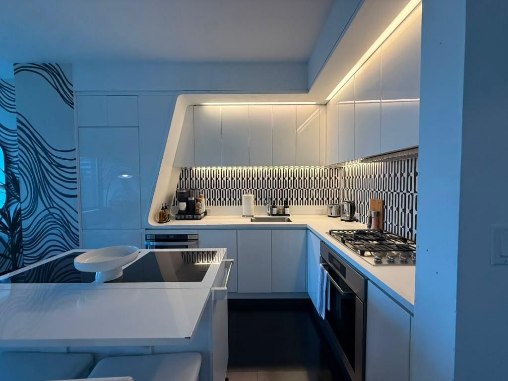 A modern kitchen with a built-in stove, a sink, and a countertop with various appliances.