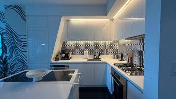A modern kitchen with a built-in stove, a sink, and a countertop with various appliances.