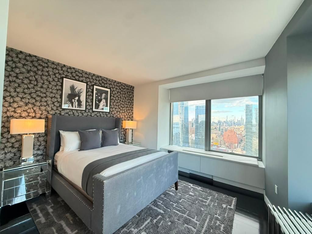 Une chambre d’hôtel moderne avec un grand lit, une vue sur la ville et un papier peint à motifs.