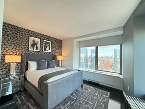 Ein modernes Hotelzimmer mit einem großen Bett, Blick auf die Stadt und einer gemusterten Tapete.