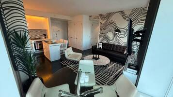 A modern living room with a dining area, a sofa, and a kitchen in the background.