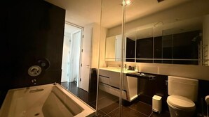 Et stilfuldt badeværelse med et stort spejl, et badekar, et toilet og en vask.