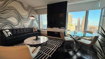 A modern living room with a black sofa, a glass coffee table, and a dining area with a glass table and chairs.